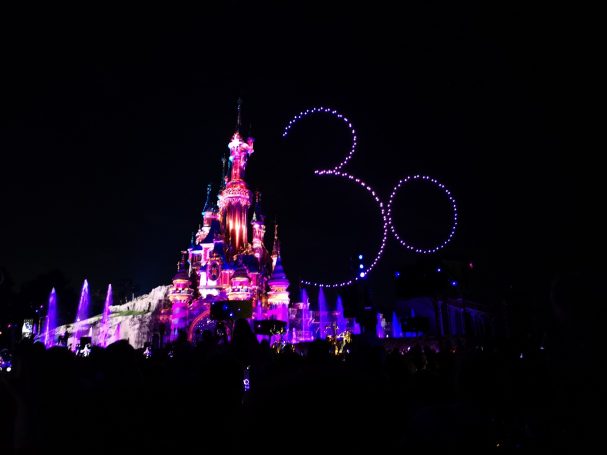 Colourful lights illuminate a castle with a large "30" overhead, celebrating an anniversary.