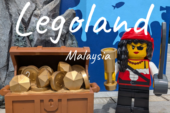 A Lego figure in pirate attire stands beside a treasure chest filled with gold pieces.