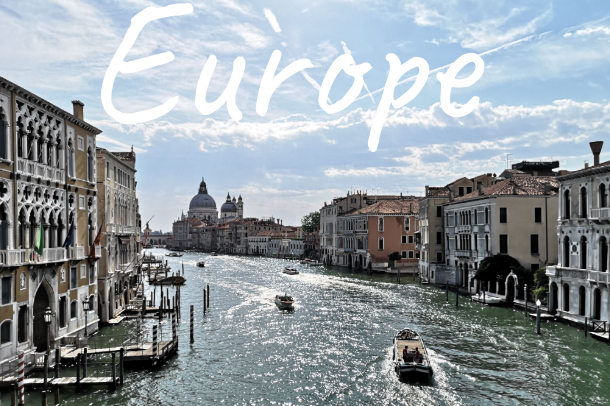 Venetian canal scene with boats and historical buildings under a cloudy sky.