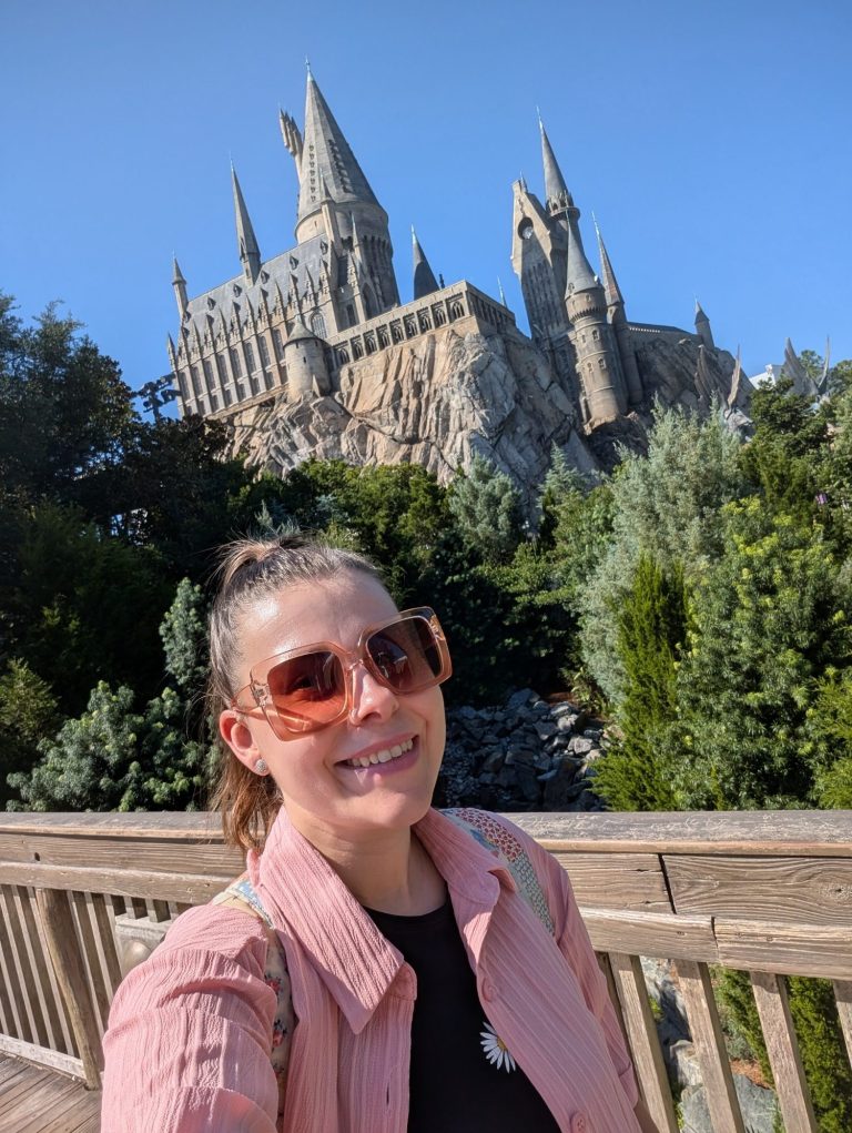 I&B's Founder smiles in front of Hogwarts Castle at Universal Studios Islands of Adventure in Orlando, which is surrounded by greenery.