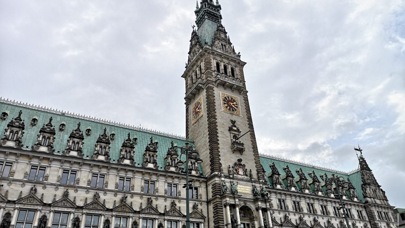 Historic building with a tall clock tower and ornate architectural details, under a cloudy sky.