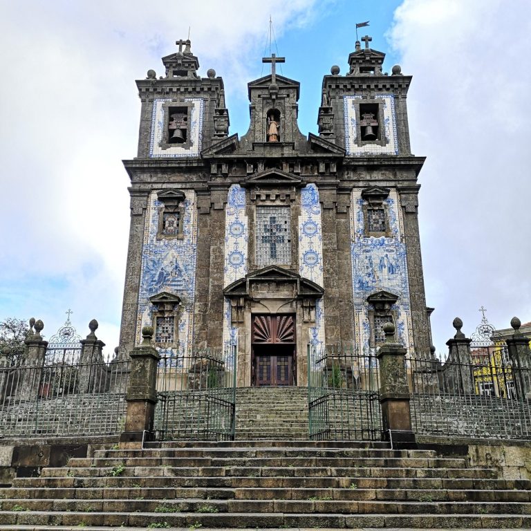 Baroque church facade with intricate blue tiles and steps leading to the entrance.