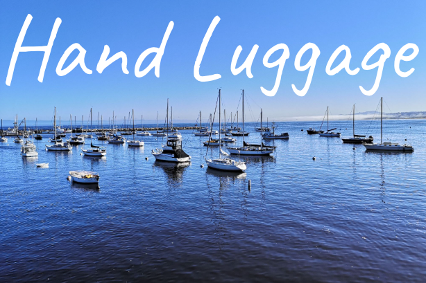 A calm blue seascape with numerous boats anchored in the water, text reads "Hand Luggage."