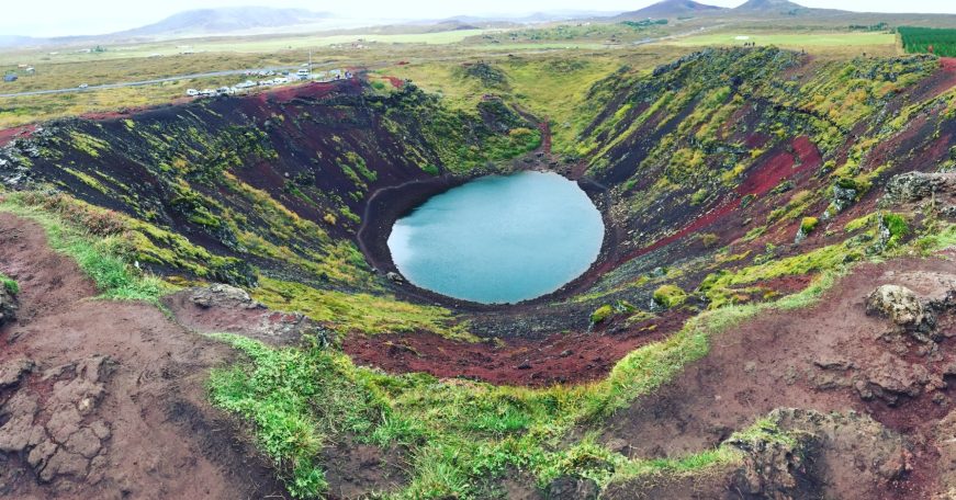 Crater lake surrounded by vibrant, moss-covered volcanic rock.