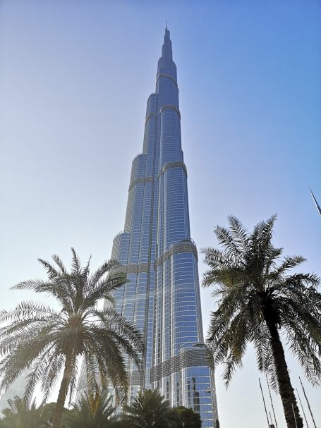 Burj Khalifa towering above palm trees under a clear blue sky.