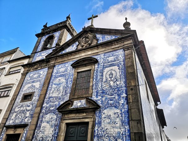 Blue and white tiled church facade with a cross and intricate architectural details.