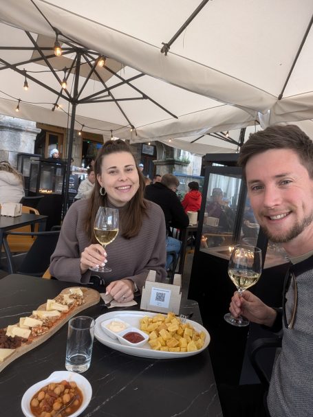 A couple enjoying food and drinks at a restaurant with outdoor seating.