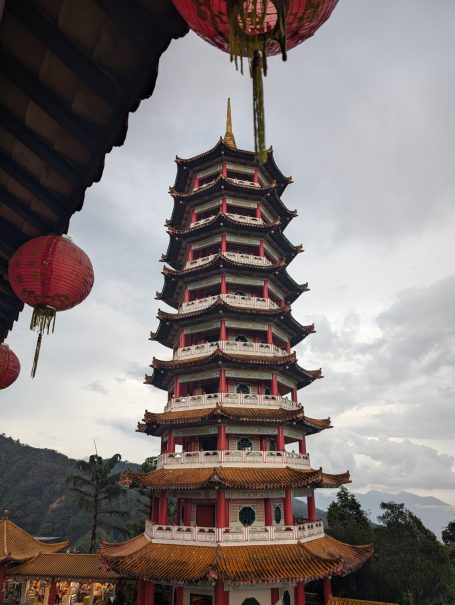 Traditional pagoda with multiple tiers, surrounded by mountains and lanterns.