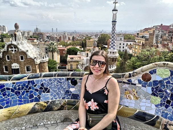 I&B's Founder posing on a mosaic balcony in Park Güell in Barcelona, with the city view in the background